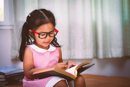 Child asian little girl is reading a book. Vintage color tone